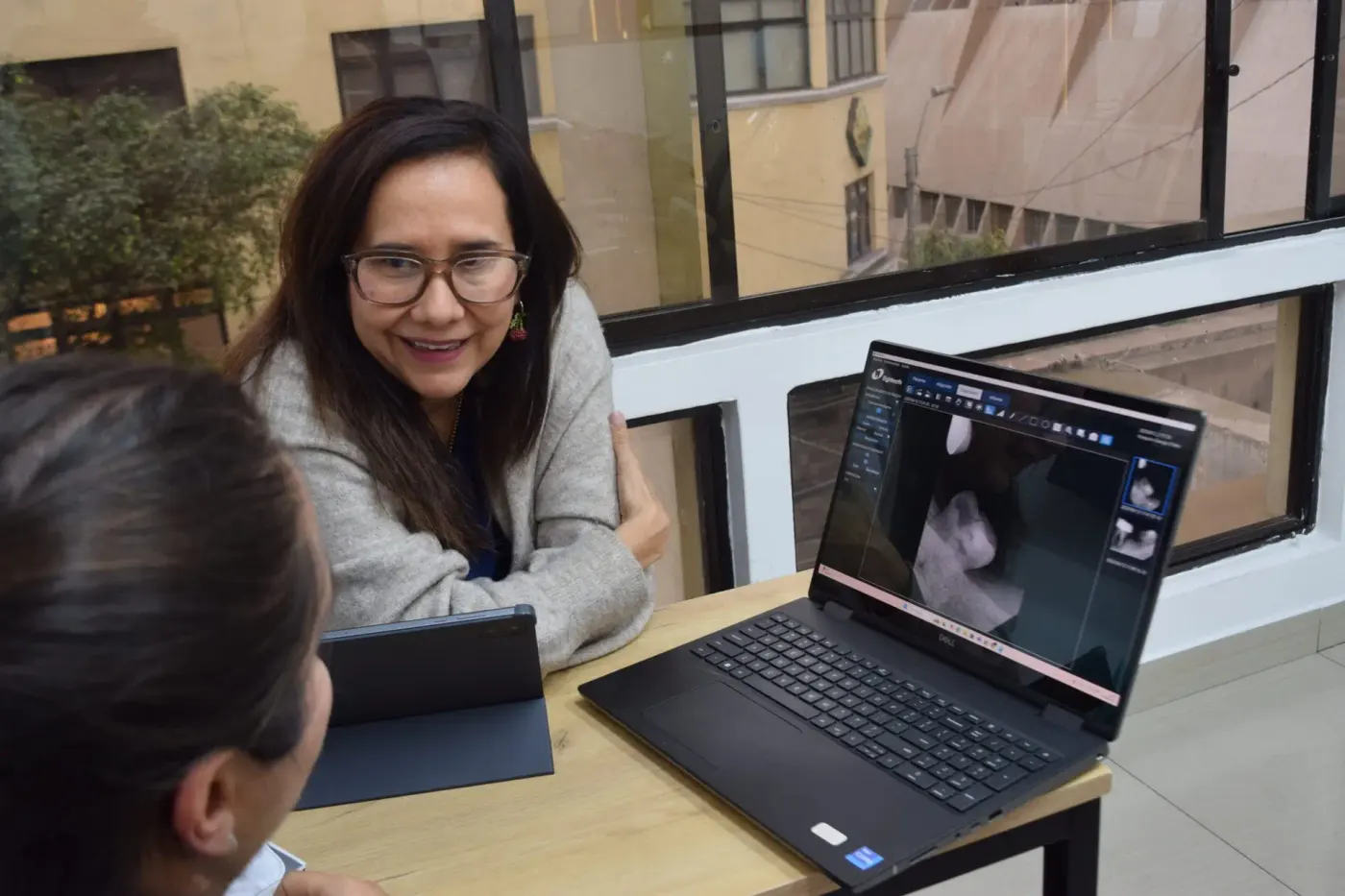Doctora conversando con una paciente frente a una laptop en la clínica